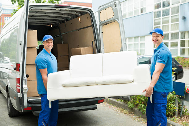 Two Happy Male Workers Putting Furniture And Boxes In Truck